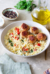 Orzo pasta with chicken meatballs, tomatoes and herbs. Italian food.