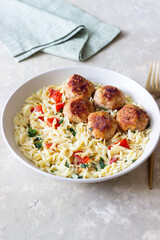 Orzo pasta with chicken meatballs, tomatoes and herbs. Italian food.