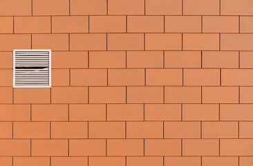 Orange bricks wall with a small ventilation window.