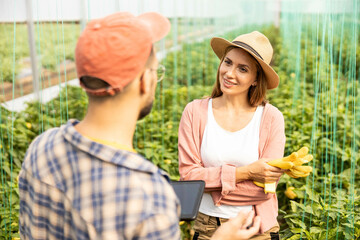 A woman and man converse in a vibrant greenhouse, showcasing collaboration and connection in...