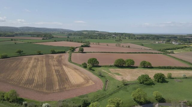 Arial view of Stogursey parish in the quantock hills Somerset. Drone moving backwards over the green fields and showing the quantocks on the background.