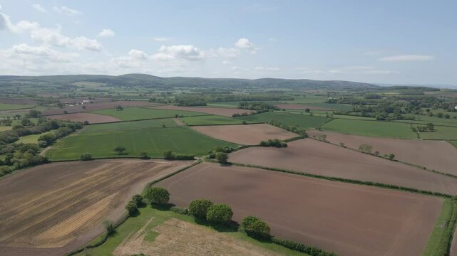 Arial view of Stogursey parish in the quantock hills Somerset. Drone slowly moving backwards over the green fields and showing the quantocks on the background. 4K 60fps.