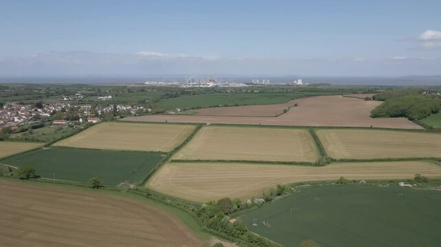 Arial view of Stogursey parish in the quantock hills Somerset. Drone rotating to the left showing the village building and Hinkley point nuclear power station on the background.