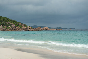 Dark storm clouds gather over a white sand beach on La Digue island in Seychelles