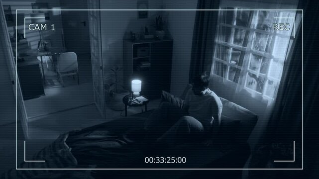 Security camera footage of man sleeping in bed then waking up scared by doors opening on their own and paranormal moving of furniture while light of lamps flickering in apartment at late night