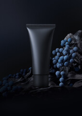 Black cream tube stands among blue decorative berries on dark background. Vertical mockup of matte plastic packaging with copy space, studio low key photo, modern still life
