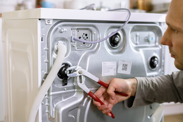 handyman repair washer at back side. washing machine repair service concept. connecting water supply to appliance.