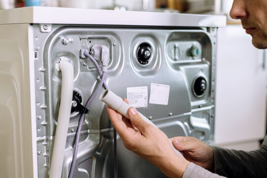 handyman repair washer at back side. washing machine repair service concept. connecting water supply to appliance.