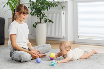 Sister and baby playing with sensory balls. Tummy time