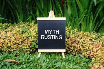 Myth Busting writing concept on a small blackboard with a background of trees.
