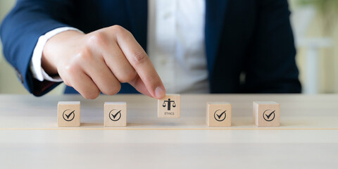 Ethical Assessment Concept. Placing wooden blocks with icons including checkmarks and a symbol of ethics, representing the evaluation and validation of ethical standards. Effective compliance.