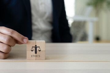 Business Ethics Concept. A person in business attire placing wooden blocks with an icon representing ethics; corporate responsibility, integrity and moral. The effective compliance and ethics culture.