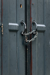 A locked black door with a chain and padlock on it, evoking associations with mystery and old-fashioned urban style. Lviv, Ukraine.