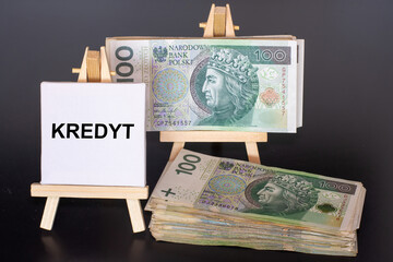 100 Polish zloty (PLN) banknotes and the word “kredyt” (credit) on miniature easels,...