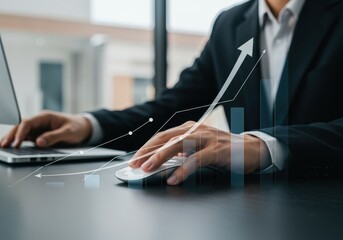 A businessman uses a computer mouse while reviewing a graph showing business growth