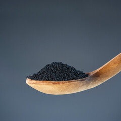 Dark nigella seeds in natural wood spoon, ideal for spice, seasoning and exotic recipe preparation concepts
