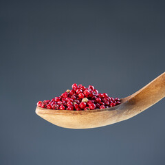Aromatic dried spice berries displayed on traditional wooden utensil, ideal for gourmet cooking and natural themes