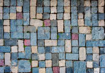 cobblestone pavement, The stones are irregularly shaped and sized, and are primarily various shades...