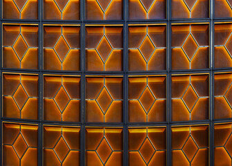 Close-up view of a wall composed of numerous square panels, each featuring an internal geometric...