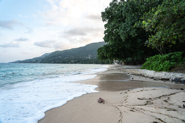 Anse Beau Vallon tropical beach in cloudy weather, ocean waves out of season on Mahe island