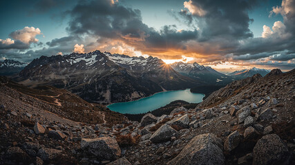 Sun setting behind snowy mountain range and turquoise lake