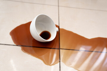 Spilled coffee, coffe puddle stain on tiled floor, messy leak with fallen cup, brown drink spillage