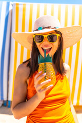 Happy woman drinking juice on a summer day at the beach