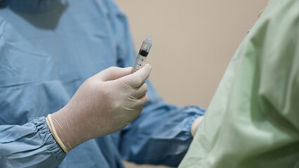 The Doctor prepares injection while wearing medical gear to vaccinate patient