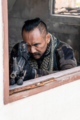 Brave soldier standing in ruined abandoned building with rifle in hands and shooting at opponent...