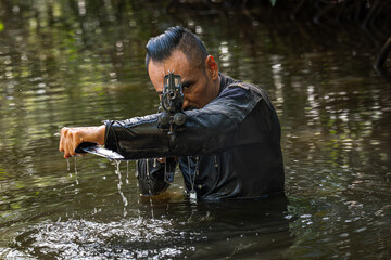 soldiers in action during river raid in the jungle waist deep in the water and mud and covering...
