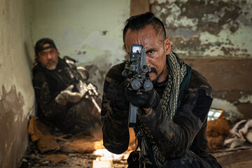 Brave soldier standing in ruined abandoned building with rifle in hands and shooting at opponent...