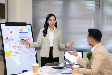Businesswoman giving a presentation with charts and graphs on a whiteboard in office
