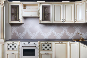 Interior of modern classic style kitchen in beige colors with golden sink basin. Drawers cabinets...