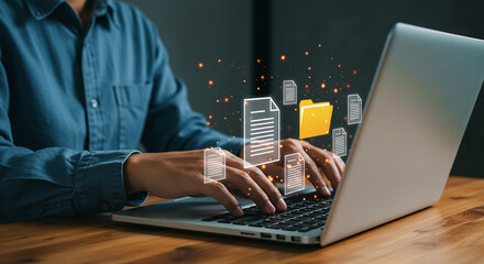 Person typing on laptop with document and folder icons floating above the keyboard on a wooden desk