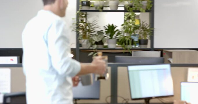 Diverse coworkers carrying French press walking office aisle pouring coffee into mug for break
