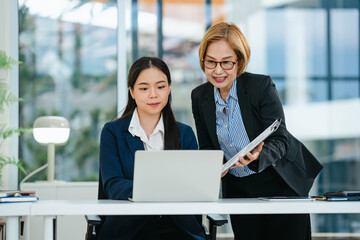 Asian supervisor and mentor guiding intern through career development process inside professional...