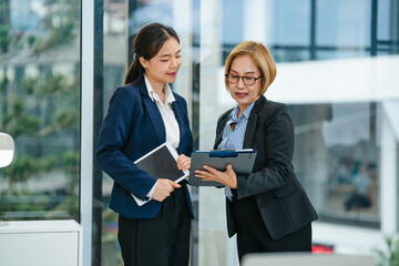Asian supervisor and mentor guiding intern through career development process inside professional...