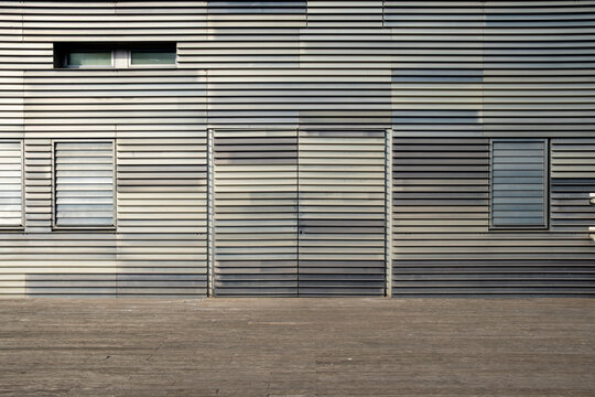 Modern architectural facade with metallic texture and horizontal rhythm, captured in urban daylight setting with strong geometry and copyspace for background use