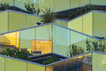Reflective glass facade with modular green terraces and integrated plants, Montpellier, France, sustainable architecture concept with urban garden innovation