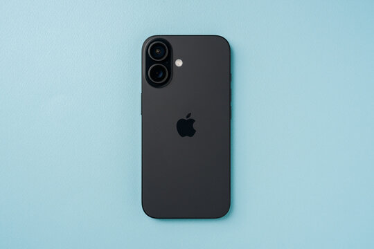 Antalya, Turkey - June 15, 2025: Top view of black iPhone 16 on blue background showing dual rear cameras