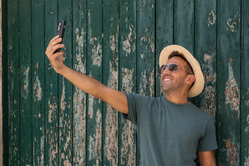 Smiling tourist taking a selfie by rustic green door in Erice, Sicily