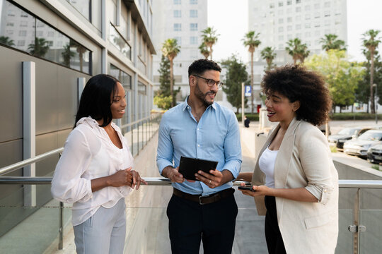 Group of Multiracial Business colleagues using digital tablet discussing a project outside office