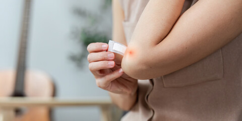 Health and Wellness. Individual applying a bandage to a minor injury on the elbow.