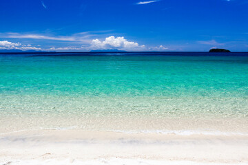 Crystal-clear turquoise Andaman sea meets pristine sandy beach under blue sky. Beautiful tropical landscape. Koh Adang, Thailand.