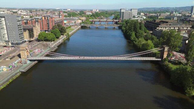 Glasgow Scotland: 18th May 2025: Glasgow City Centre hotels. Bridges over the River Clyde on a sunny day drone footage. south portland street suspension bridge