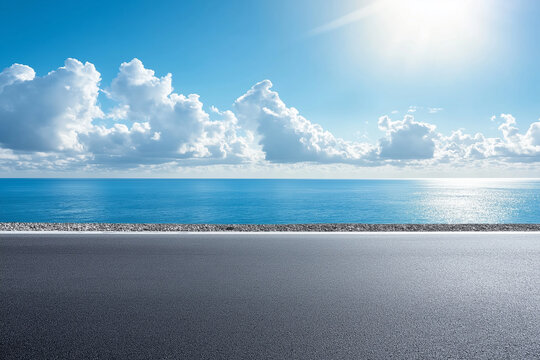 Asphalt road leading to ocean with clear blue sky, great for vacation banners or transportation concepts