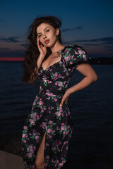 Woman in dress posing standing at pier near sea at the evening