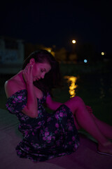 Woman in red light sitting at the night pier