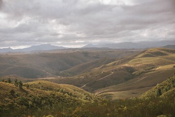 Naklejka premium Scenic view of rolling hills under a cloudy sky.