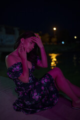 Woman in red light sitting at the night pier